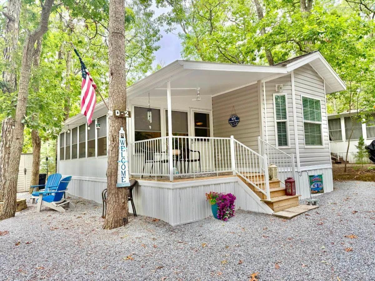 Screened Florida room on a light gray park model under the trees