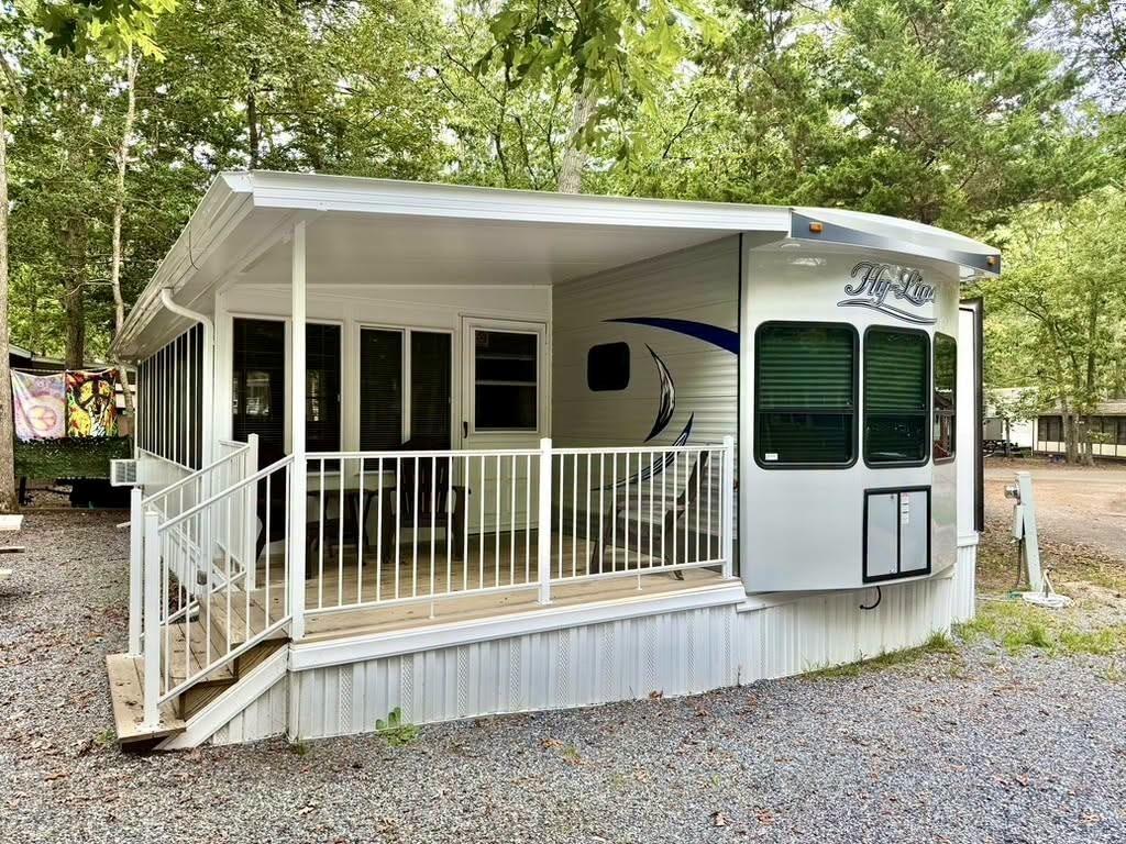 Hy-Line trailer with a covered Florida room, deck, and white railings